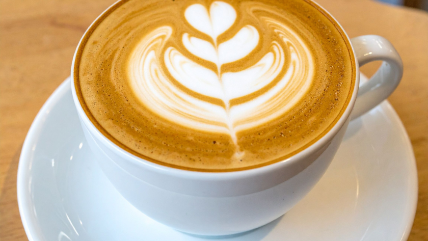 Latte con arte en una taza de cerámica sobre mesa.